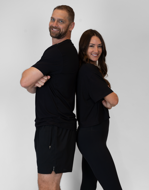 man and woman standing back to back with man wearing men's black 6" airflow shorts