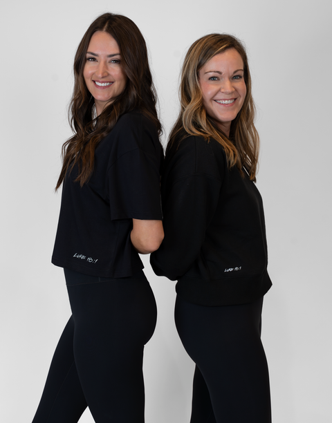 Two woman standing back to back one wearing Ladies Black Relaxed Fleece Crew