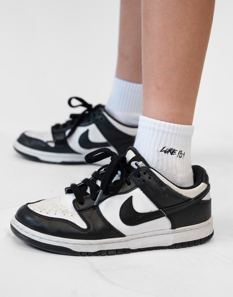person wearing white socks with Luke 18:1 text in black