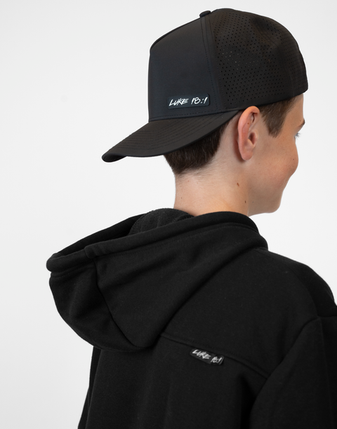 person wearing backward black hat with "LUKE 18:1" text