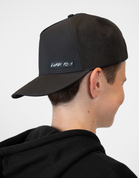 person wearing backward black hat with "LUKE 18:1" text