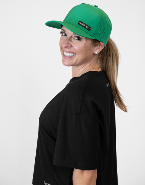 Woman wearing kelly green hat with "LUKE 18:1" text