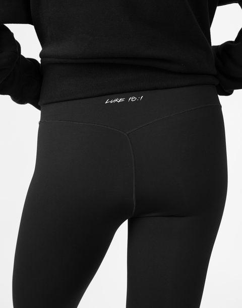 rear view of person wearing black Ladies Performance Legging with "LUKE 18:1" text on waistband
