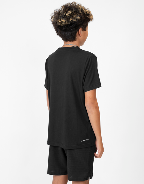 Rear view of boy wearing Youth black Bamboo Performance Tee with "LUKE 18:1" text on back above lower seam