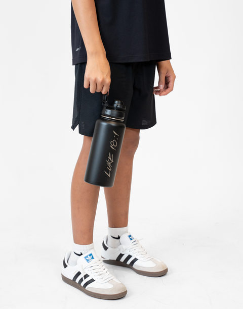Person holding a black water bottle with 'Luke 18:1' text on a white background