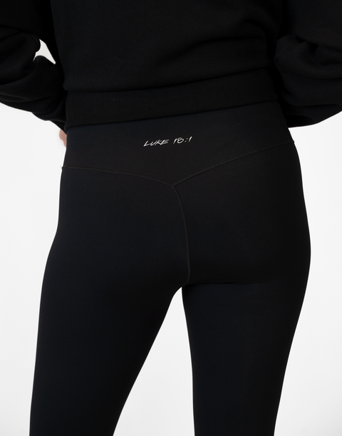 rear view of person wearing black Ladies Performance Legging with "LUKE 18:1" text on waistband