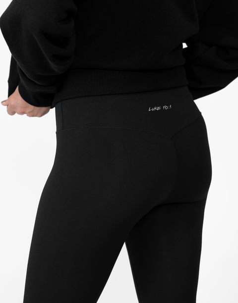 rear view of person wearing black Ladies Performance Legging with "LUKE 18:1" text on waistband