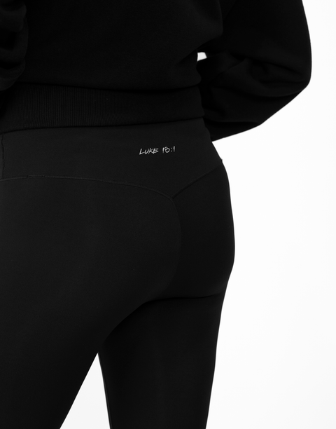 rear view of person wearing black Ladies Performance Legging with "LUKE 18:1" text on waistband