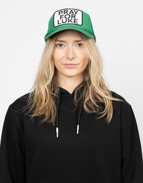 Person wearing a green cap with 'Pray for Luke' patch