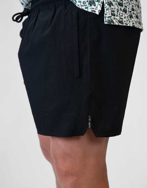 side view of man wearing Men's Black 6" Airflow Short showing "LUKE 18:1" text on side seam