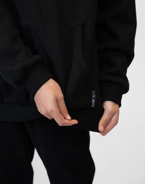 person wearing Youth Black Fleece Hoodie showing "LUKE 18:1" text next to pocket