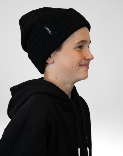 side view of person wearing black beanie with "LUKE 18:1" text