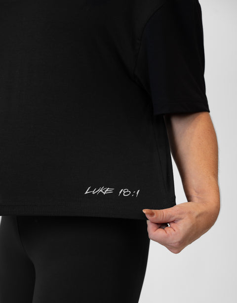 Woman wearing ladies Bamboo Mid-Crop Tee with "Luke 18:1" text above bottom seam