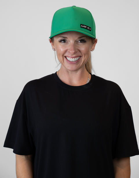Woman wearing kelly green hat with "LUKE 18:1" text