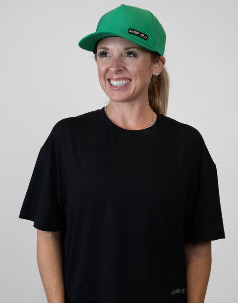 Woman wearing kelly green hat with "LUKE 18:1" text