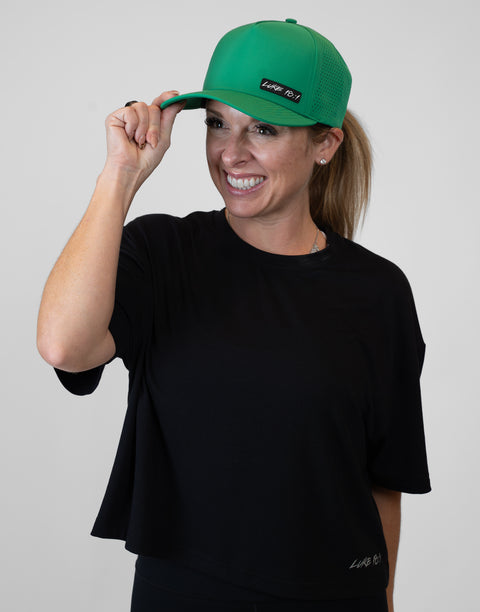Woman wearing kelly green hat with "LUKE 18:1" text