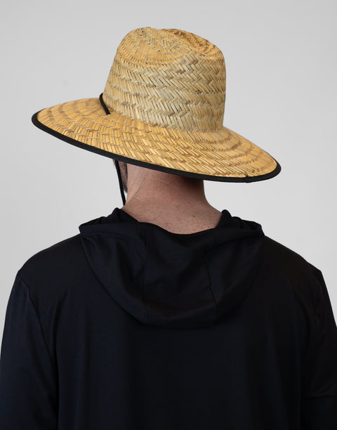 Person wearing a straw hat with a black band on a plain background