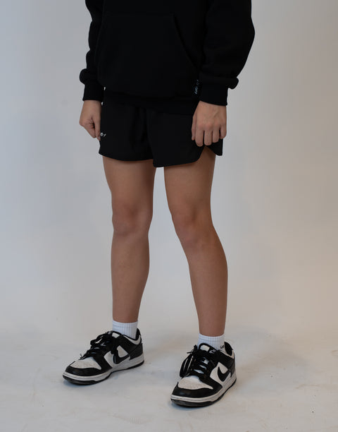 Girl wearing girls black flowy performance short with "LUKE 18:1" text