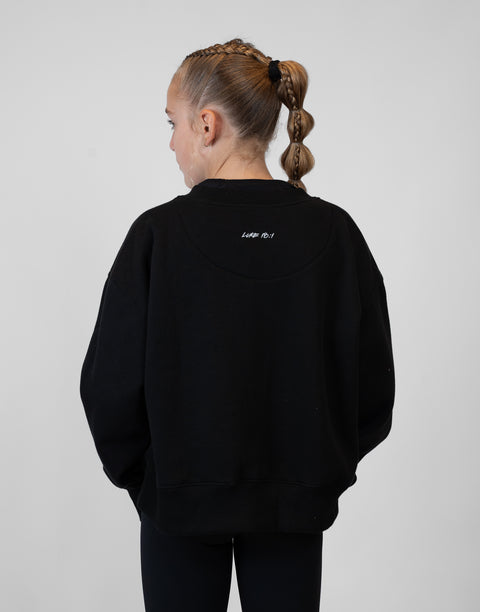 rear view of girl wearing Ladies Black Relaxed Fleece Crew with "LUKE 18:1" text on upper back