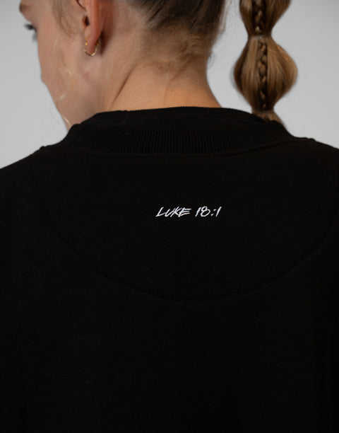 rear view of girl wearing Ladies Black Relaxed Fleece Crew with "LUKE 18:1" text on upper back
