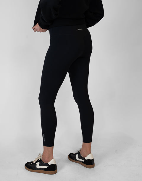 rear view of person wearing black Ladies Performance Legging with "LUKE 18:1" text on waistband