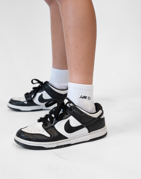 person wearing white socks with Luke 18:1 text in black