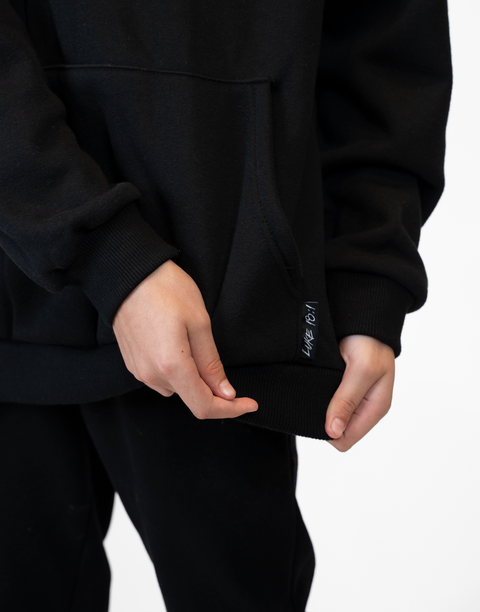 person wearing Youth Black Fleece Hoodie showing "LUKE 18:1" text next to pocket