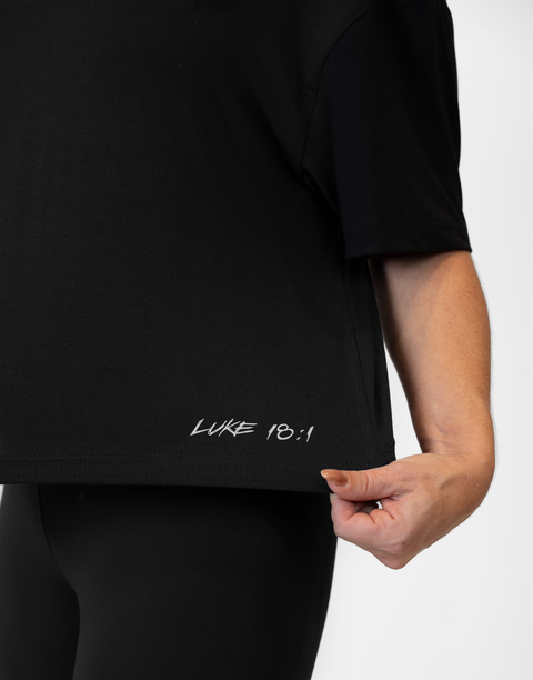 Woman wearing ladies Bamboo Mid-Crop Tee with "Luke 18:1" text above bottom seam
