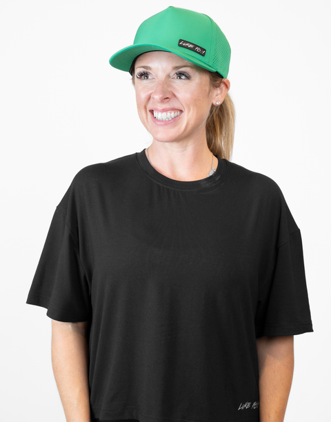 Woman wearing kelly green hat with "LUKE 18:1" text