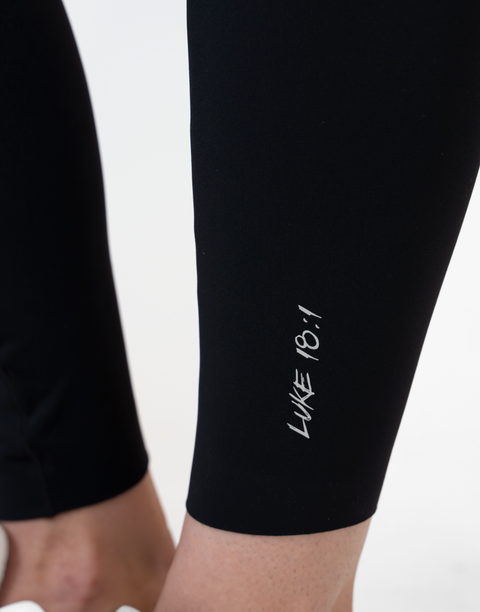 closeup of black Ladies Performance Legging with "LUKE 18:1" text on ankle