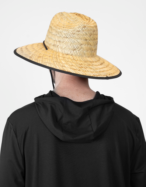 Person wearing a straw hat with a black band on a plain background