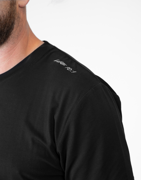 Man wearing Men's black Bamboo Performance Tee showing "LUKE 18:1" text on shoulder