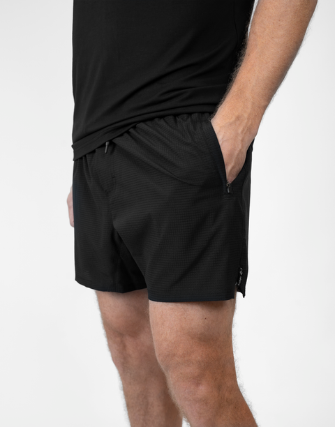 side view of man wearing Men's Black 6" Airflow Short showing "LUKE 18:1" text on side seam