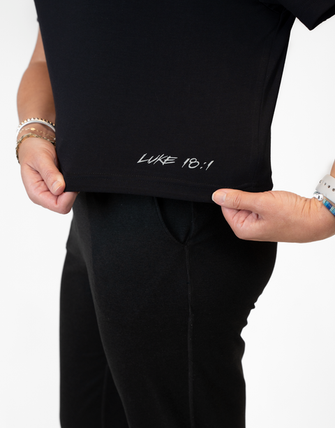 Woman wearing ladies Bamboo Mid-Crop Tee with "Luke 18:1" text above bottom seam