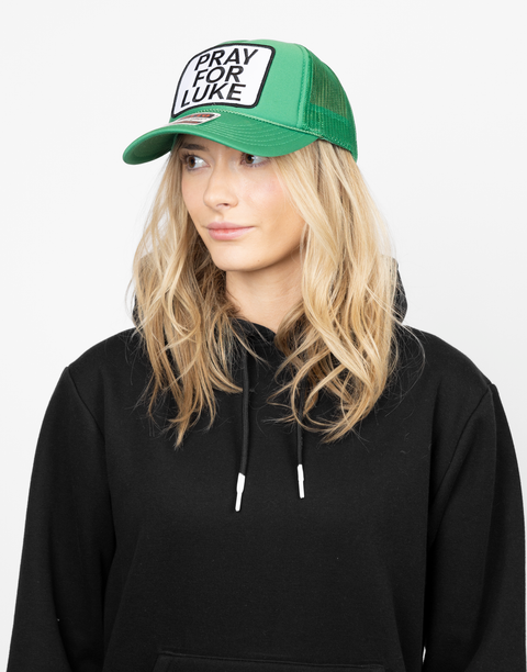 Person wearing a green cap with 'Pray for Luke' patch