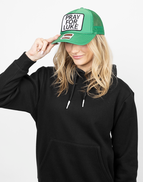 Person wearing a green cap with 'Pray for Luke' patch
