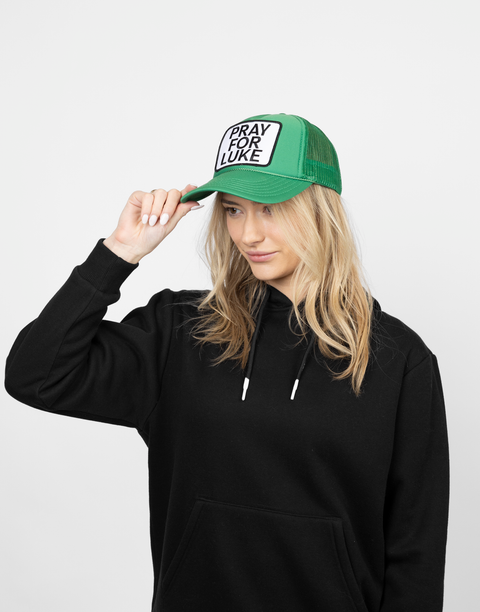 Person wearing a green cap with 'Pray for Luke' patch