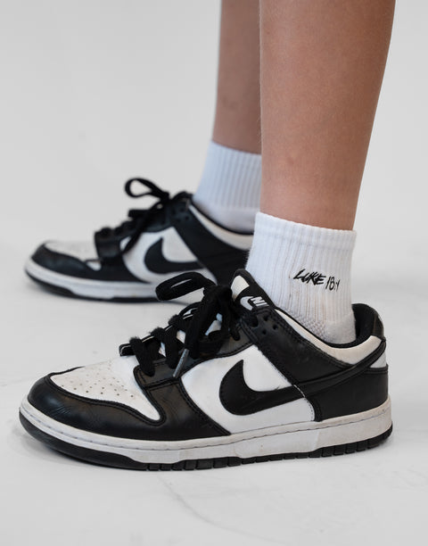 person wearing white socks with Luke 18:1 text in black