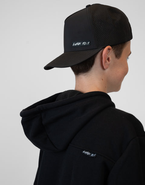 person wearing backward black hat with "LUKE 18:1" text