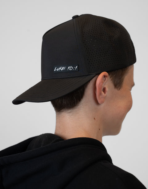 person wearing backward black hat with "LUKE 18:1" text
