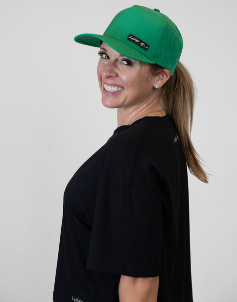 Woman wearing kelly green hat with "LUKE 18:1" text