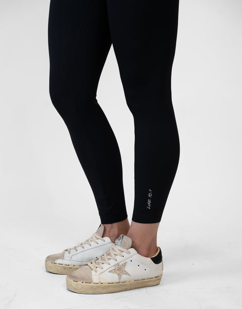 side view of person wearing black Ladies Performance Legging with "LUKE 18:1" text on ankle