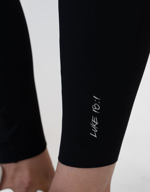 closeup of black Ladies Performance Legging with "LUKE 18:1" text on ankle