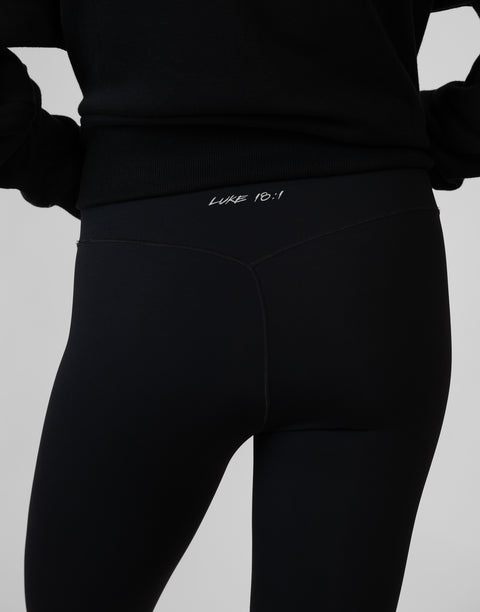 rear view of person wearing black Ladies Performance Legging with "LUKE 18:1" text on waistband