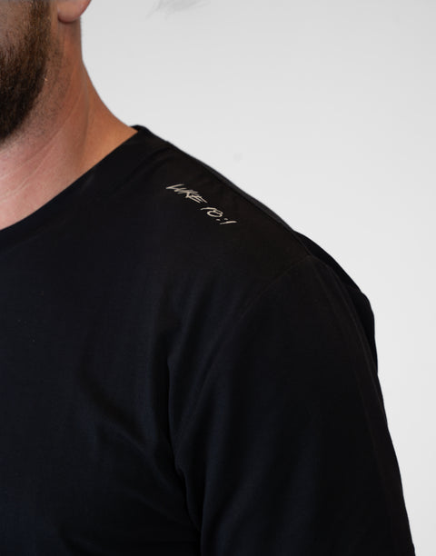 Man wearing Men's black Bamboo Performance Tee showing "LUKE 18:1" text on shoulder