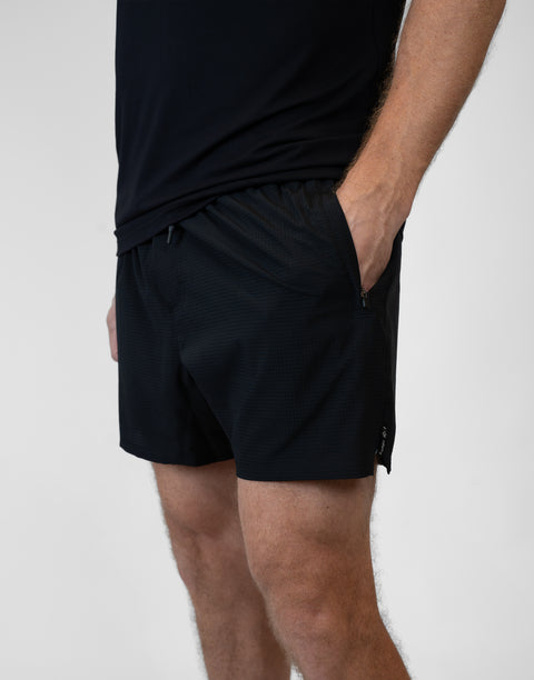 side view of man wearing Men's Black 6" Airflow Short showing "LUKE 18:1" text on side seam