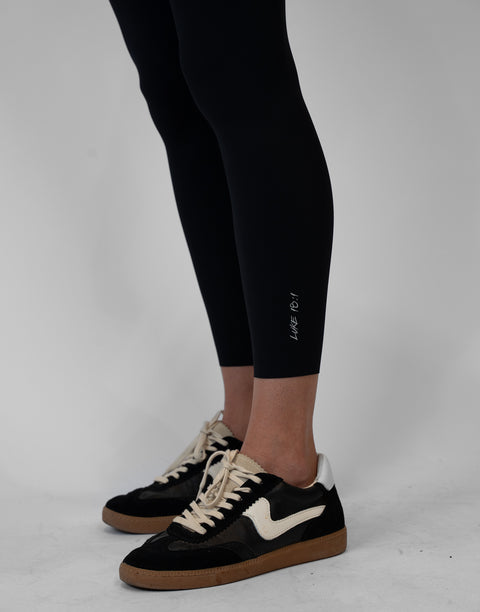 closeup of black Ladies Performance Legging with "LUKE 18:1" text on ankle