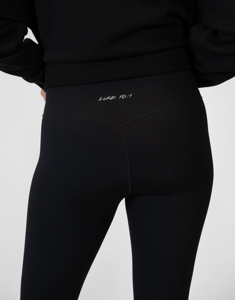 rear view of person wearing black Ladies Performance Legging with "LUKE 18:1" text on waistband