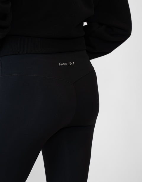 rear view of person wearing black Ladies Performance Legging with "LUKE 18:1" text on waistband