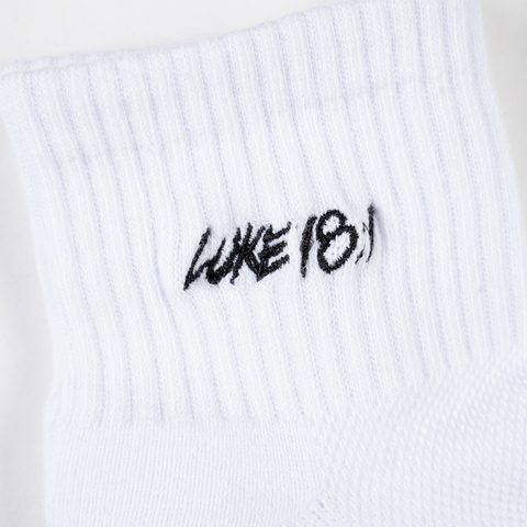 Closeup of white socks with black "LUKE 18:1" text on ankle
